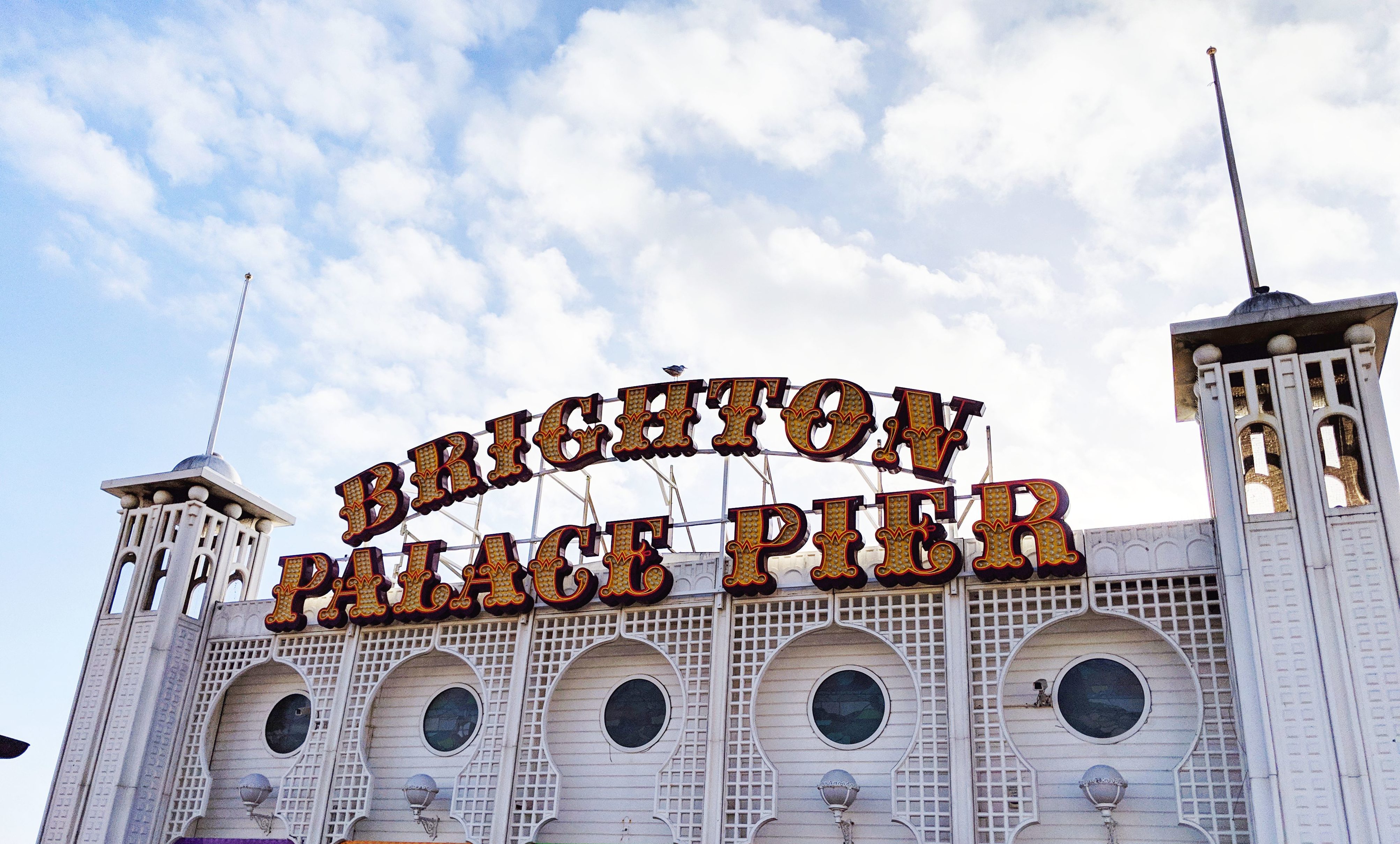 brighton palace pier neon sign blue cloudy sky background